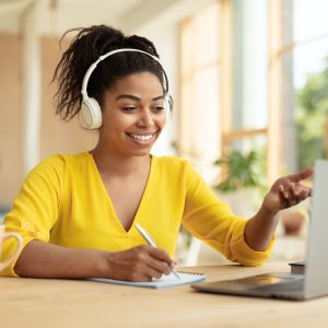 Online education concept. Happy black female student in headphones having video call via laptop