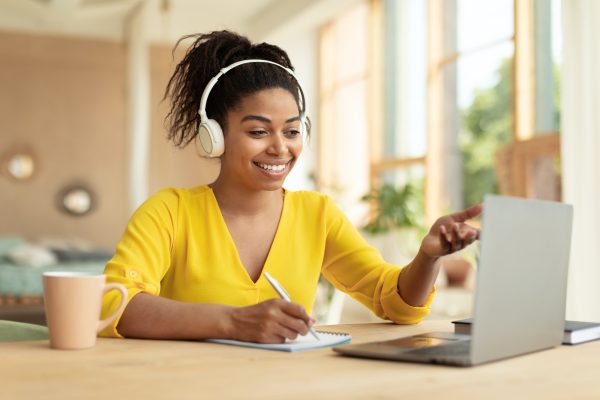 Online education concept. Happy black female student in headphones having video call via laptop